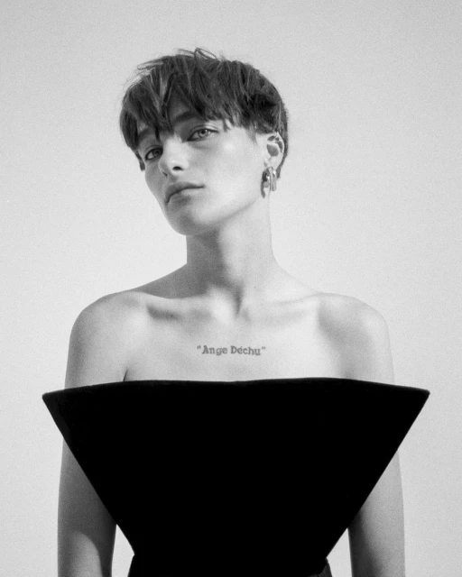 Striking black and white portrait of an adult woman with short hair wearing a modern black top against a white backdrop.