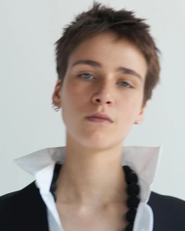 Portrait of a person with short brown hair wearing a white collared shirt and black jacket by photographer Kira Bunse