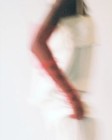 Motion blurred photographic portrait of a person wearing a red sleeve against a plain white background