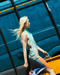 A blonde woman in a halter dress walking past a vibrant blue van with graphic text, captured by photographer Kira Bunse.