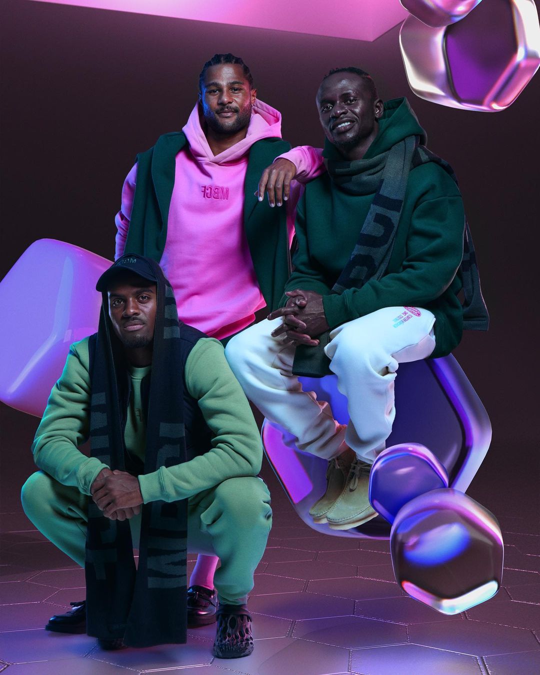 Three men pose in athletic streetwear against a gradient backdrop with floating geometric shapes and studio lighting, fashion shoot.