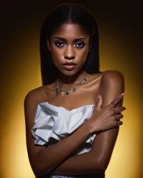 Portrait of a Black woman wearing a white ruffled top and silver charm necklace against a warm yellow gradient background.