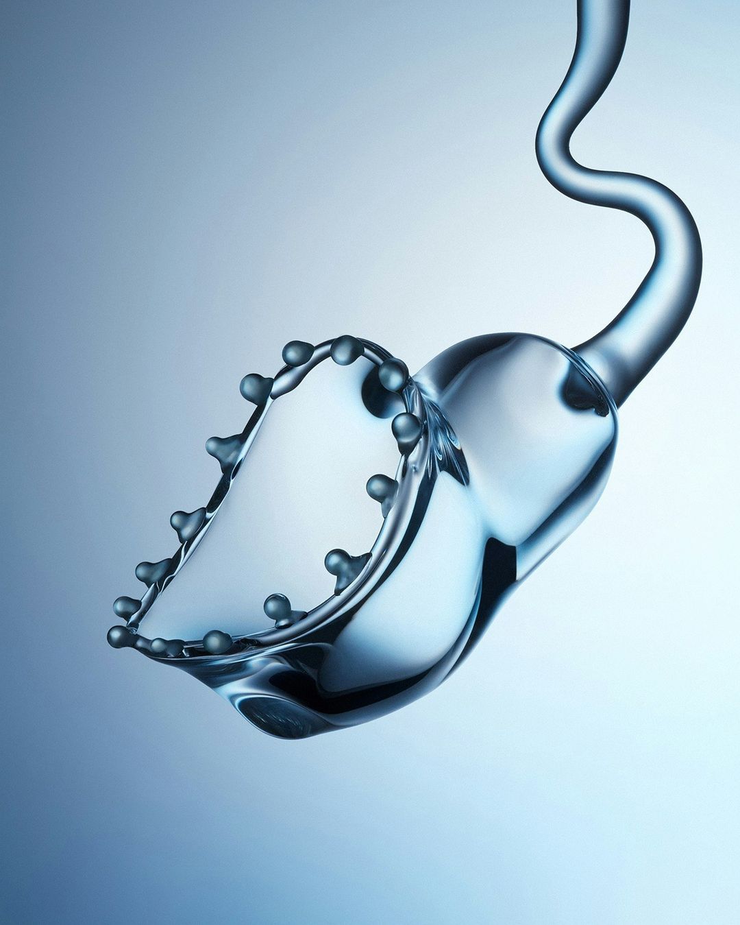 Abstract close-up of liquid splashing upward with droplets against a light blue gradient background in an artistic studio photograph.