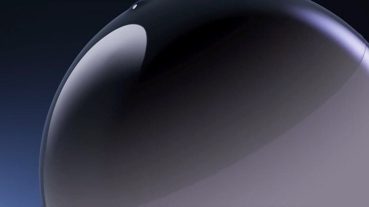 Close-up studio shot of a glossy, semi-translucent, dome-shaped object with gradient color shifts on a dark blue background.