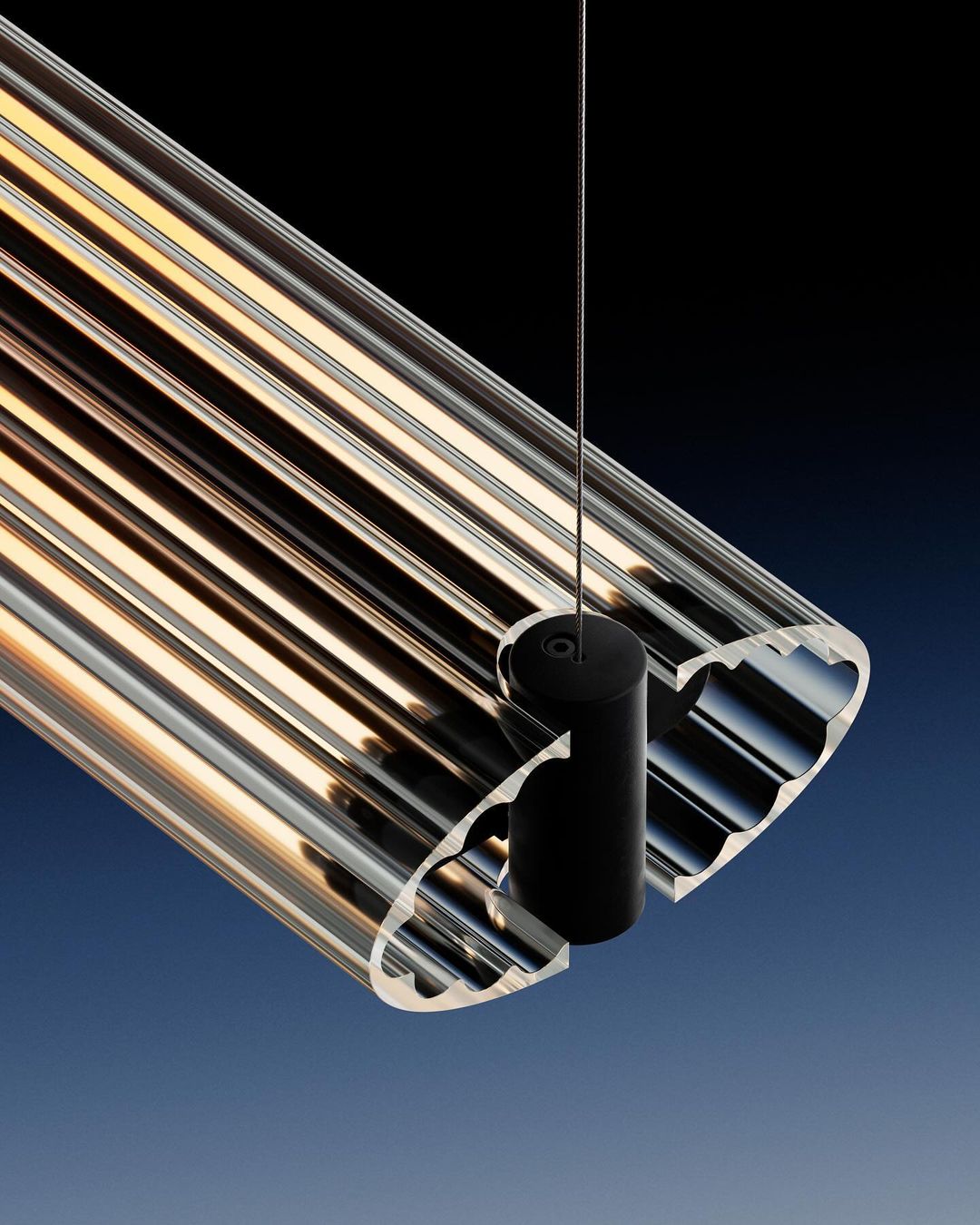 Contemporary lighting fixture made of transparent ribbed acrylic suspended by a cable in a high-key interior setting.