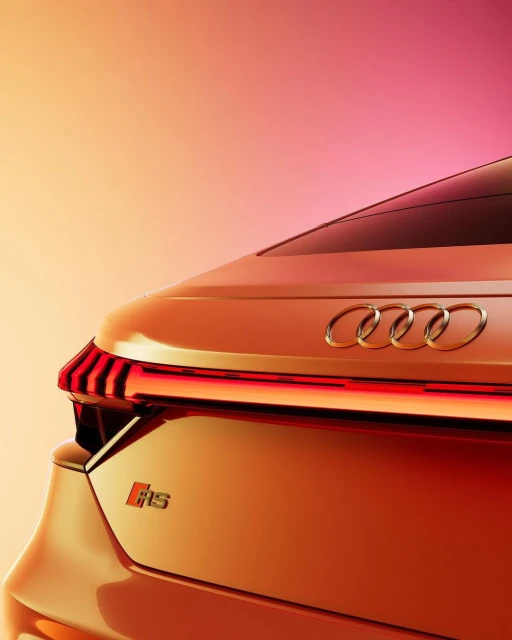 Close-up of the rear of a bronze Audi RS e-tron GT with a sleek design, illuminated taillights, and the Audi logo in a studio setting.