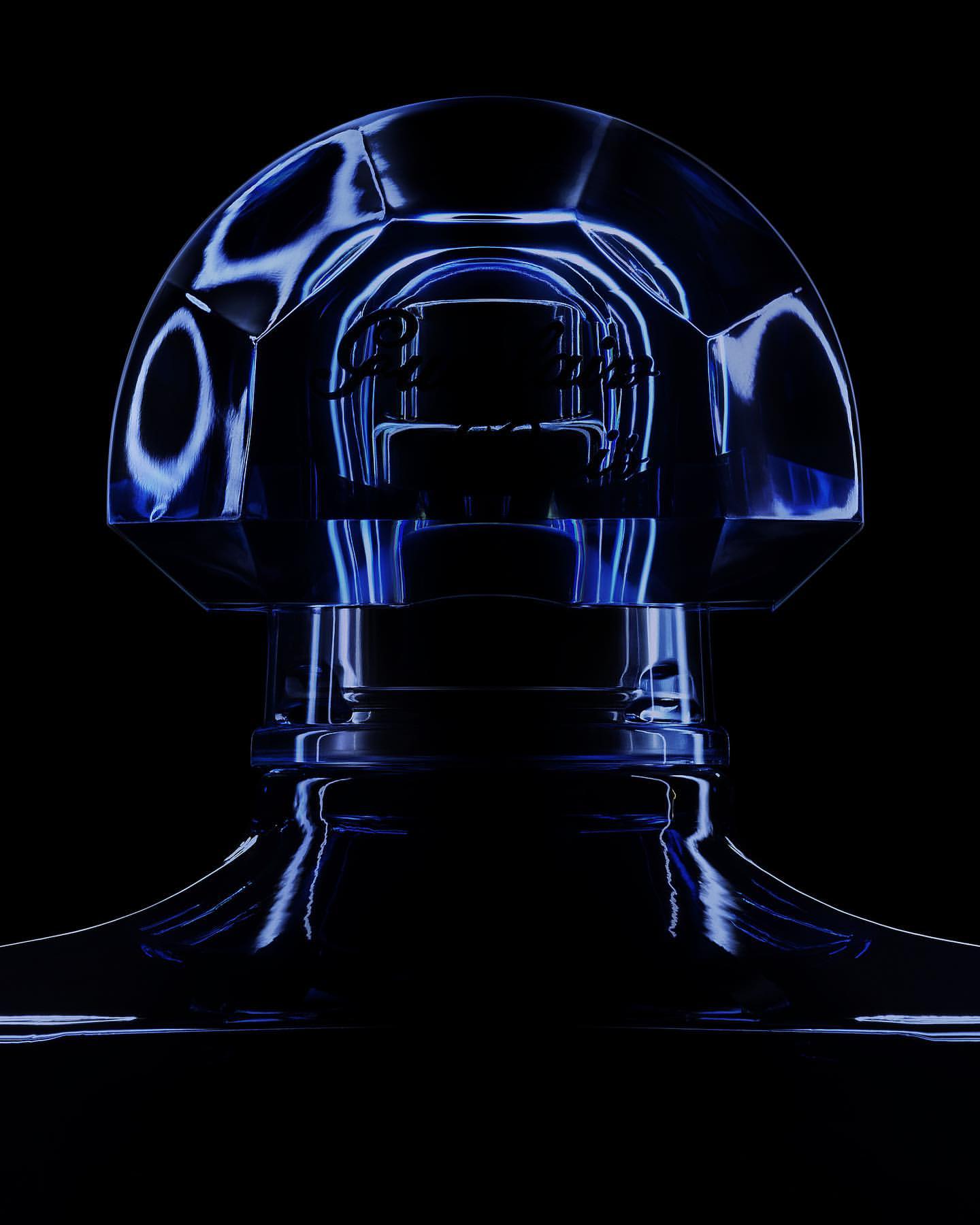 Close-up of a translucent blue crystal perfume bottle, with dark background and subtle lighting enhancing its faceted structure.