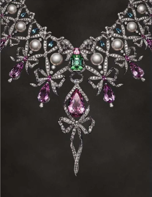 Exquisite jeweled necklace featuring diamonds, pearls, and colored gems in a bow design on a dark background. Jewelry, diamonds, gems.