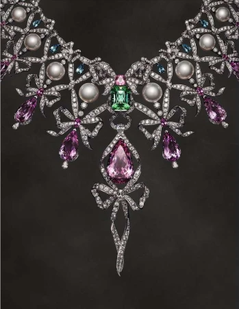 Exquisite jeweled necklace featuring diamonds, pearls, and colored gems in a bow design on a dark background. Jewelry, diamonds, gems.