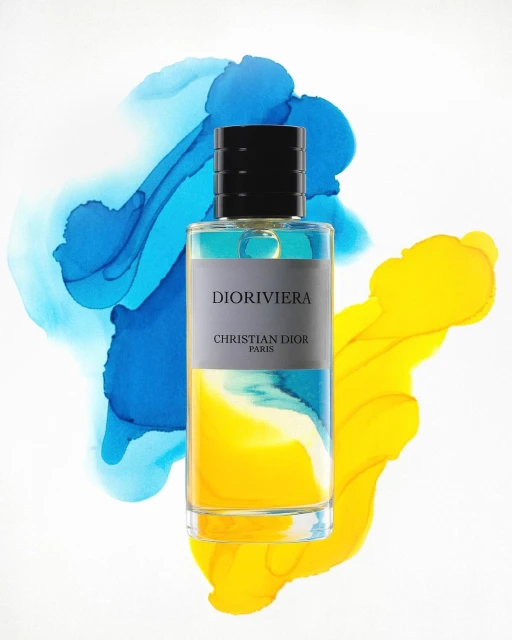 Studio shot of Dioriviera perfume bottle against abstract blue and yellow paint swirls on a white background, product photography.