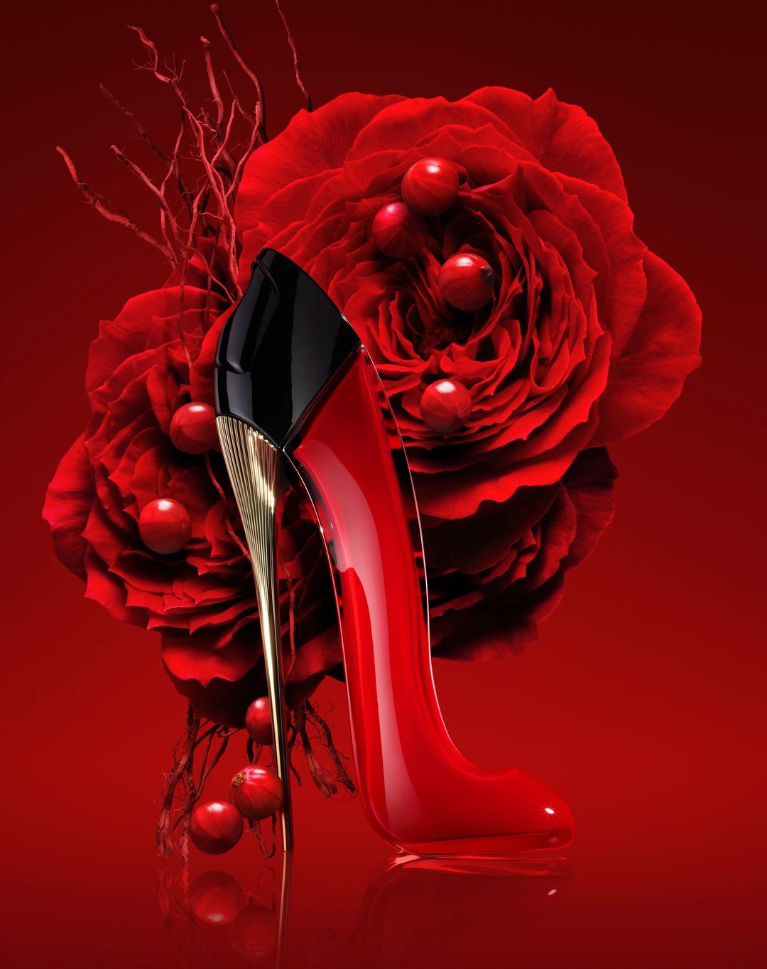 Elegant red stiletto perfume bottle displayed with matching red roses and berries, set against a rich red backdrop.