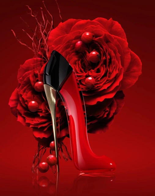 Elegant red stiletto perfume bottle displayed with matching red roses and berries, set against a rich red backdrop.
