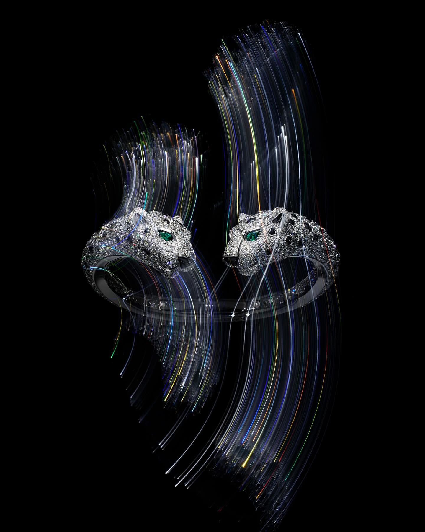 Two jaguar head rings with white gemstone embellishments are dynamically positioned against a black background with light streak accents.