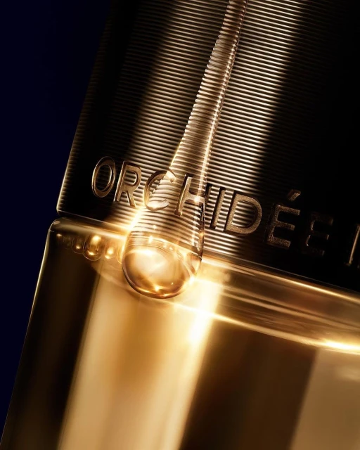Close-up of a gold beauty product bottle featuring embossed horizontal lines and the brand name ORCHIDÉE IMPÉRIALE along its side.