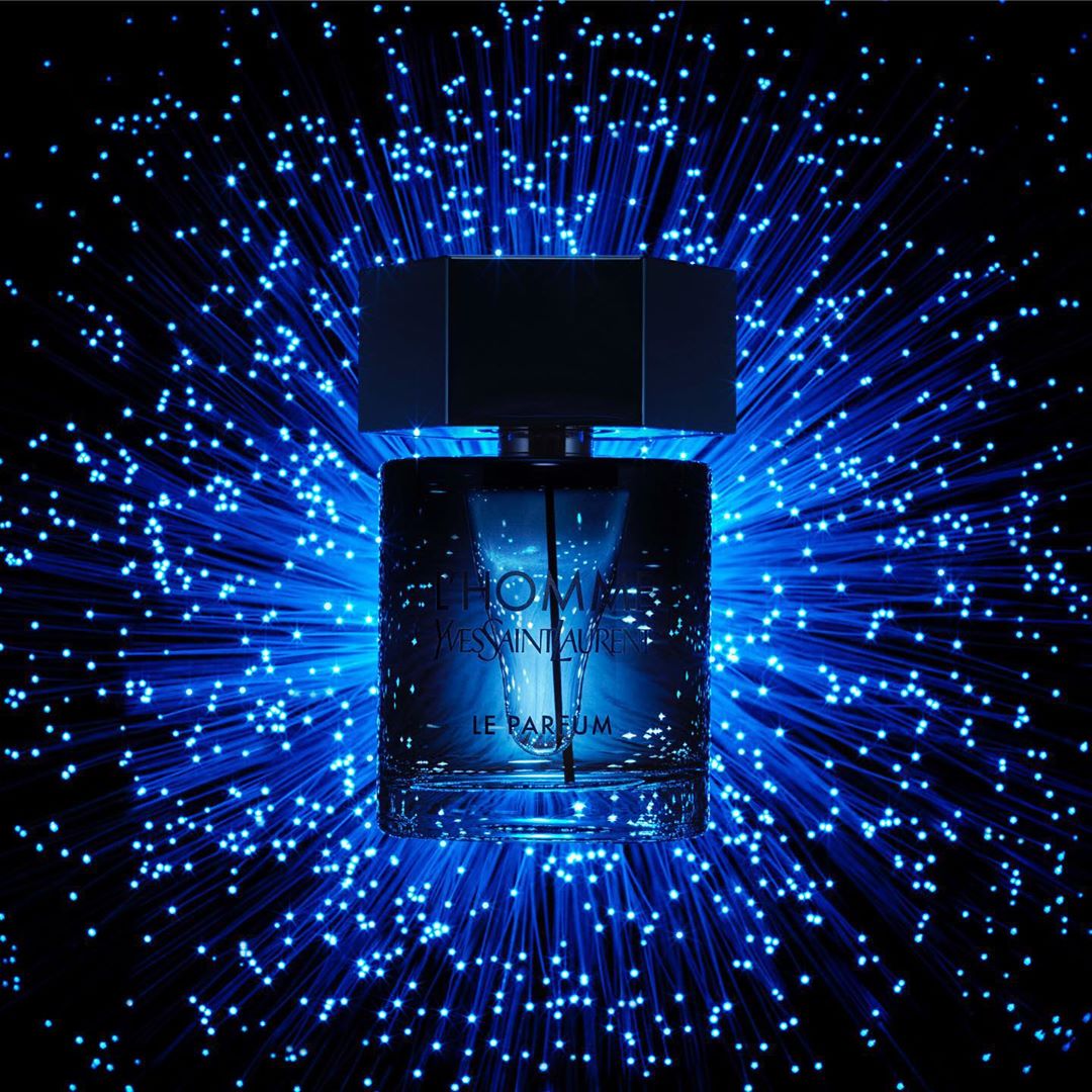 A perfume bottle with a square cap stands against a backdrop of blue fibre optic lights, highlighting the brand's elegance.