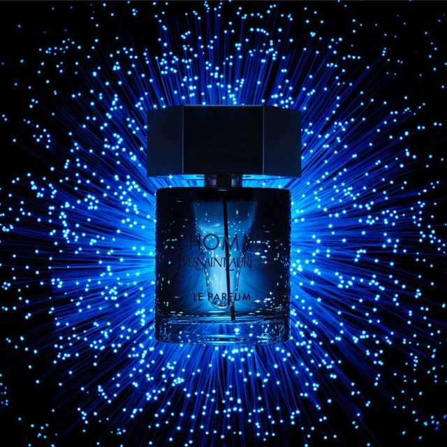 A perfume bottle with a square cap stands against a backdrop of blue fibre optic lights, highlighting the brand's elegance.