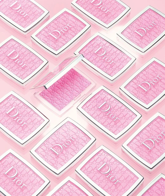Overhead shot of multiple Dior blush compacts in a light pink hue, neatly arranged on a matching light pink surface.