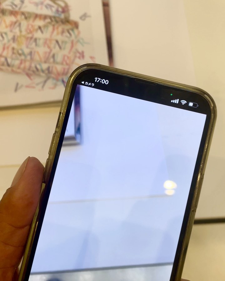 Image of a cellphone displaying a mostly white screen with top bar details such as time and battery life visible; object on table.