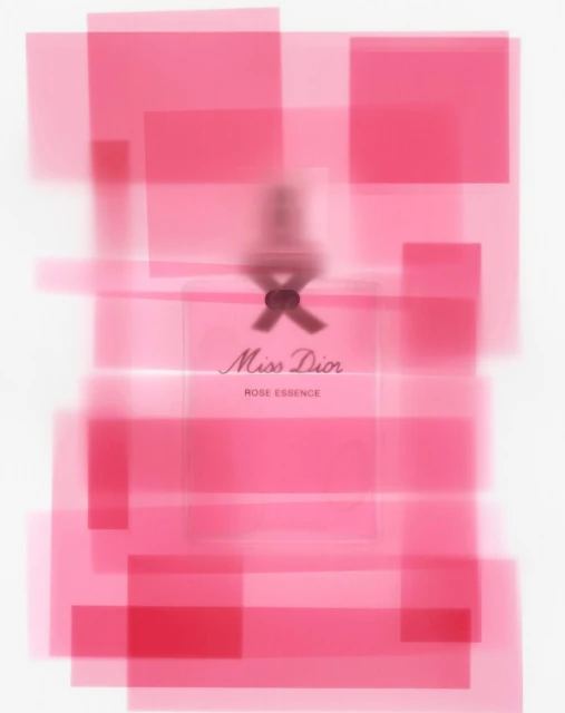 Studio shot of a perfume bottle, Miss Dior Rose Essence, with soft pink geometric shapes in the background and soft, diffused lighting.