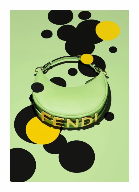 A light green Fendi handbag is showcased against a matching light green background with black and yellow circle accents.