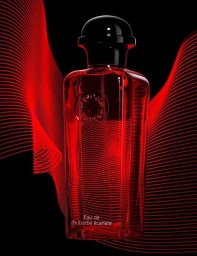 Red perfume bottle with a black cap against a dark background featuring glowing red light trails