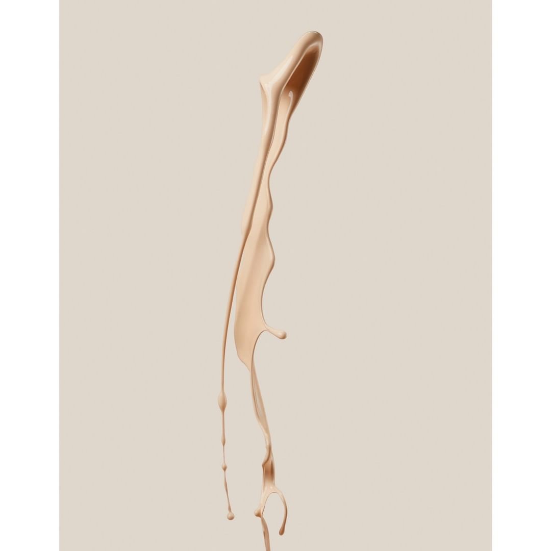 Isolated studio shot of light beige liquid foundation splash, showcasing smooth texture and fluid motion against a neutral background.