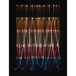Textured multicolored woven wall hanging sculpture against a solid black background photographed by Kosuke Nishimura.