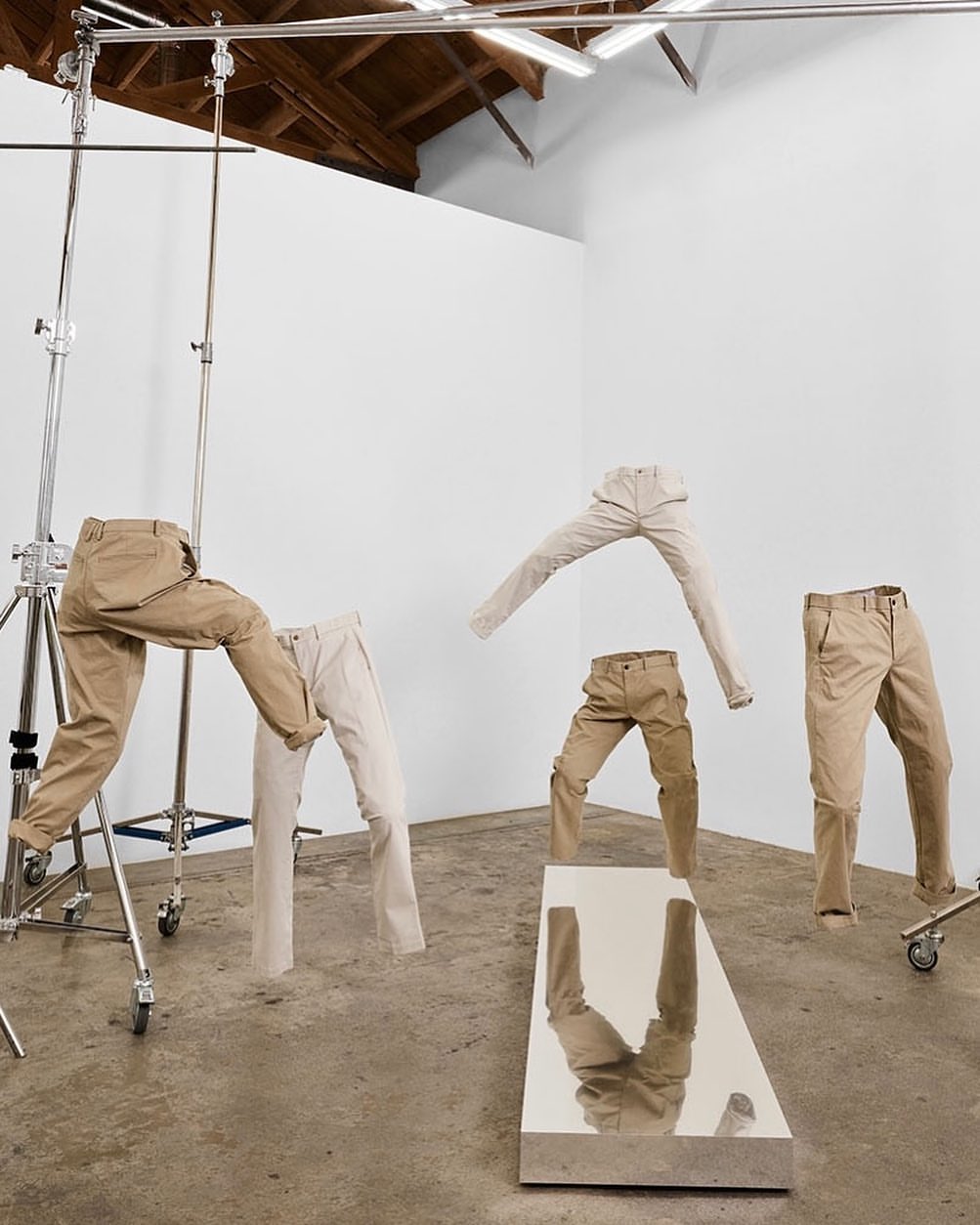 Fashion-forward conceptual image featuring a collection of neutral-toned pants displayed in a photo studio setting, creating a unique visual.