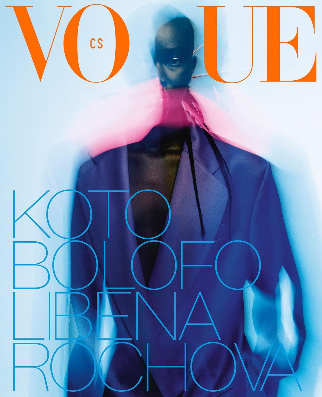 Vogue magazine cover featuring a blurry full figure portrait of an adult female wearing a blue jacket and sunglasses on a white background.