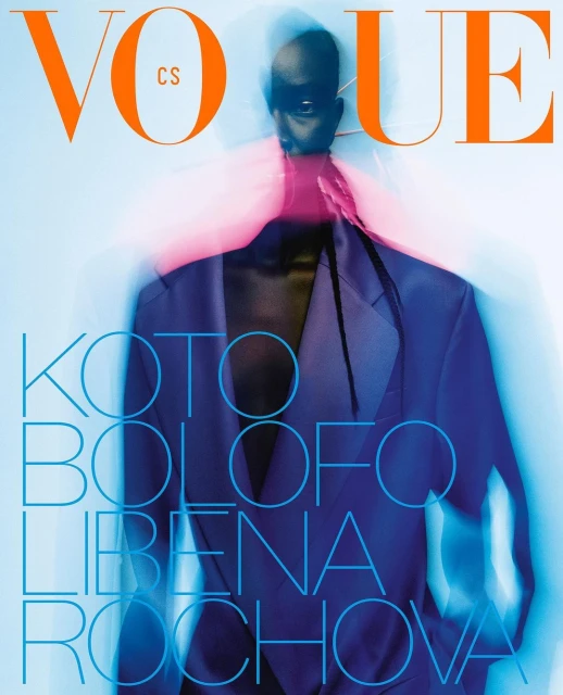 Vogue magazine cover featuring a blurry full figure portrait of an adult female wearing a blue jacket and sunglasses on a white background.