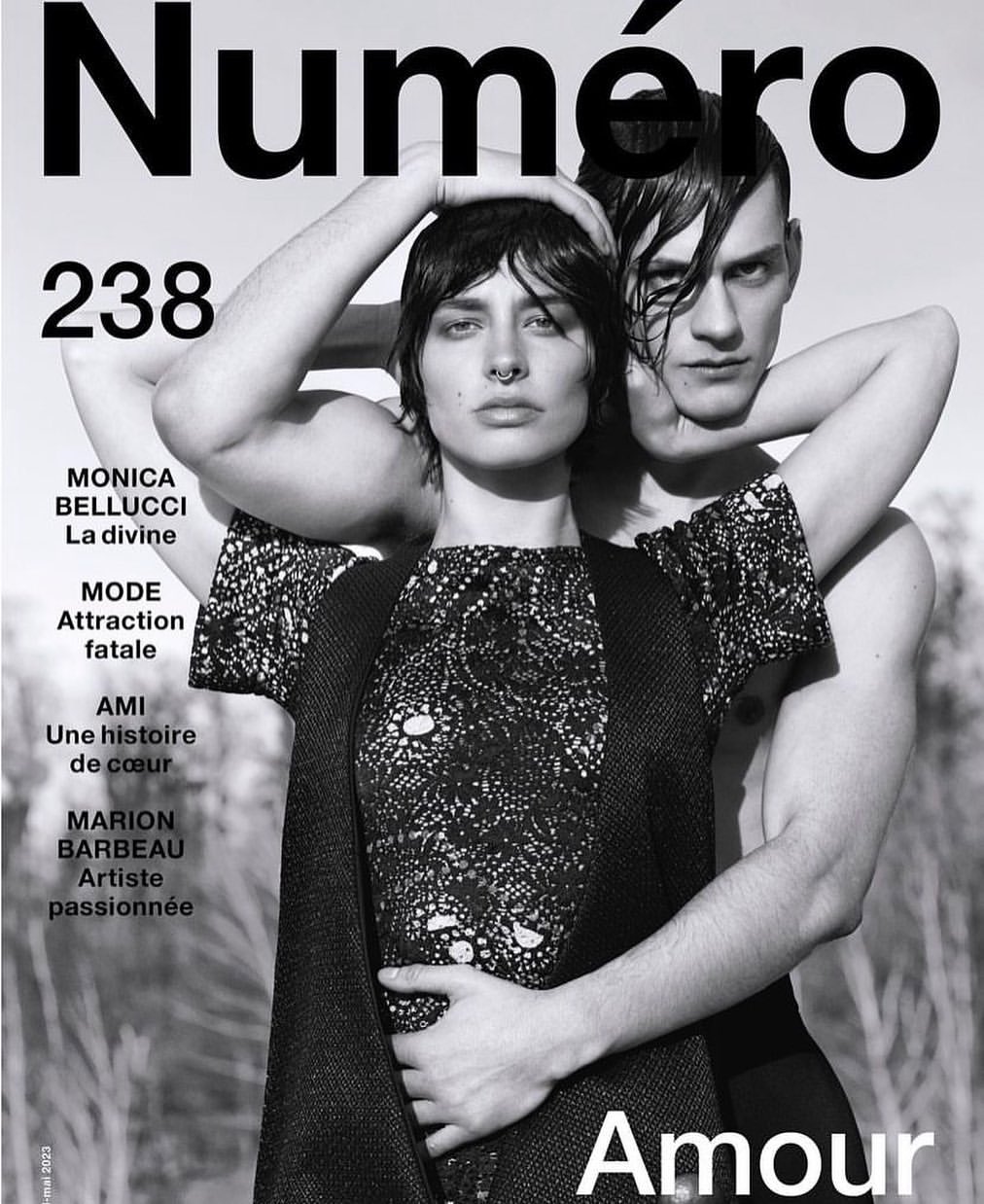 Black-and-white fashion magazine cover featuring two models, one woman with a septum piercing and dark hair, and one bare-chested man.