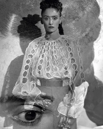 Monochromatic portrait of an adult woman with braided hair, wearing an ornate white blouse, contrasted with an oversized eye and shadow.