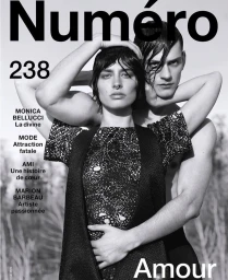 Black and white magazine cover featuring a woman with dark hair and a shirtless man embracing her from behind.