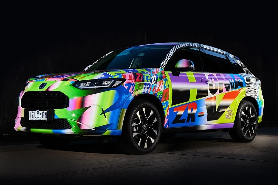 Vibrant custom-painted Honda ZR-V SUV featuring graffiti-style graphics, black rims, and a dark, neutral background.