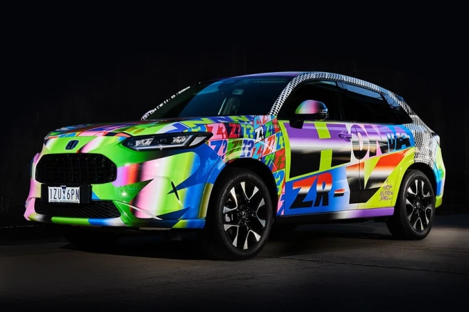 Vibrant custom-painted Honda ZR-V SUV featuring graffiti-style graphics, black rims, and a dark, neutral background.