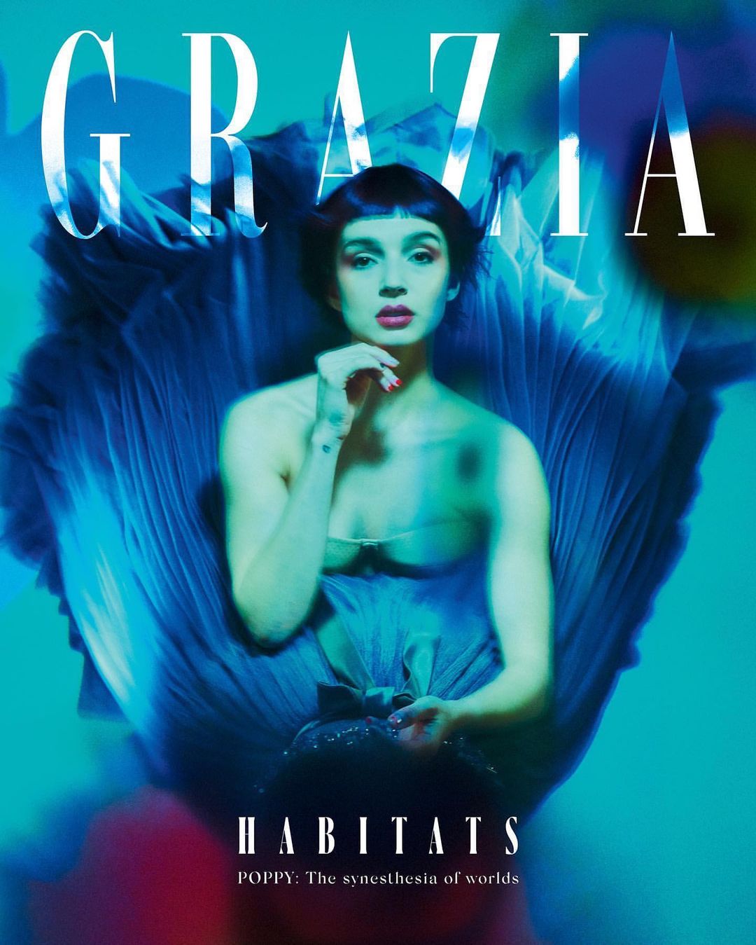Magazine cover featuring a young woman with a blue floral background and Grazia masthead. The main subject is Poppy in 'Habitats'.