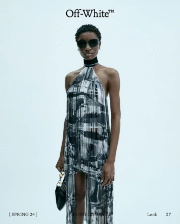 Model in printed halter dress and sunglasses holding a black handbag against a pale grey background