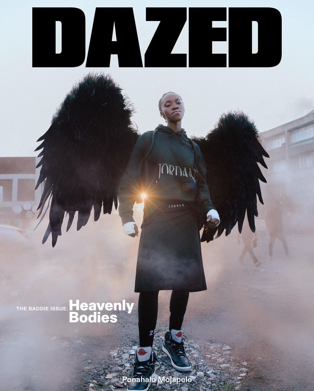 Dazed magazine cover features a woman with dark wings wearing a Jordan hoodie and black skirt against a blurred background.