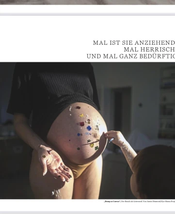 Pregnant adult female with belly art showing flower designs being touched by a child's hand in an indoor environment.