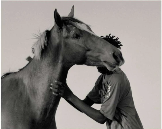 Black man standing beside a horse against a plain light background photographed by Kwabena Sekyi Appiah-nti