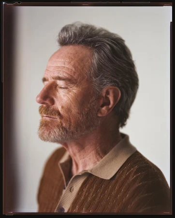 Profile portrait of Bryan Cranston with eyes closed, wearing a textured brown polo shirt against a plain background