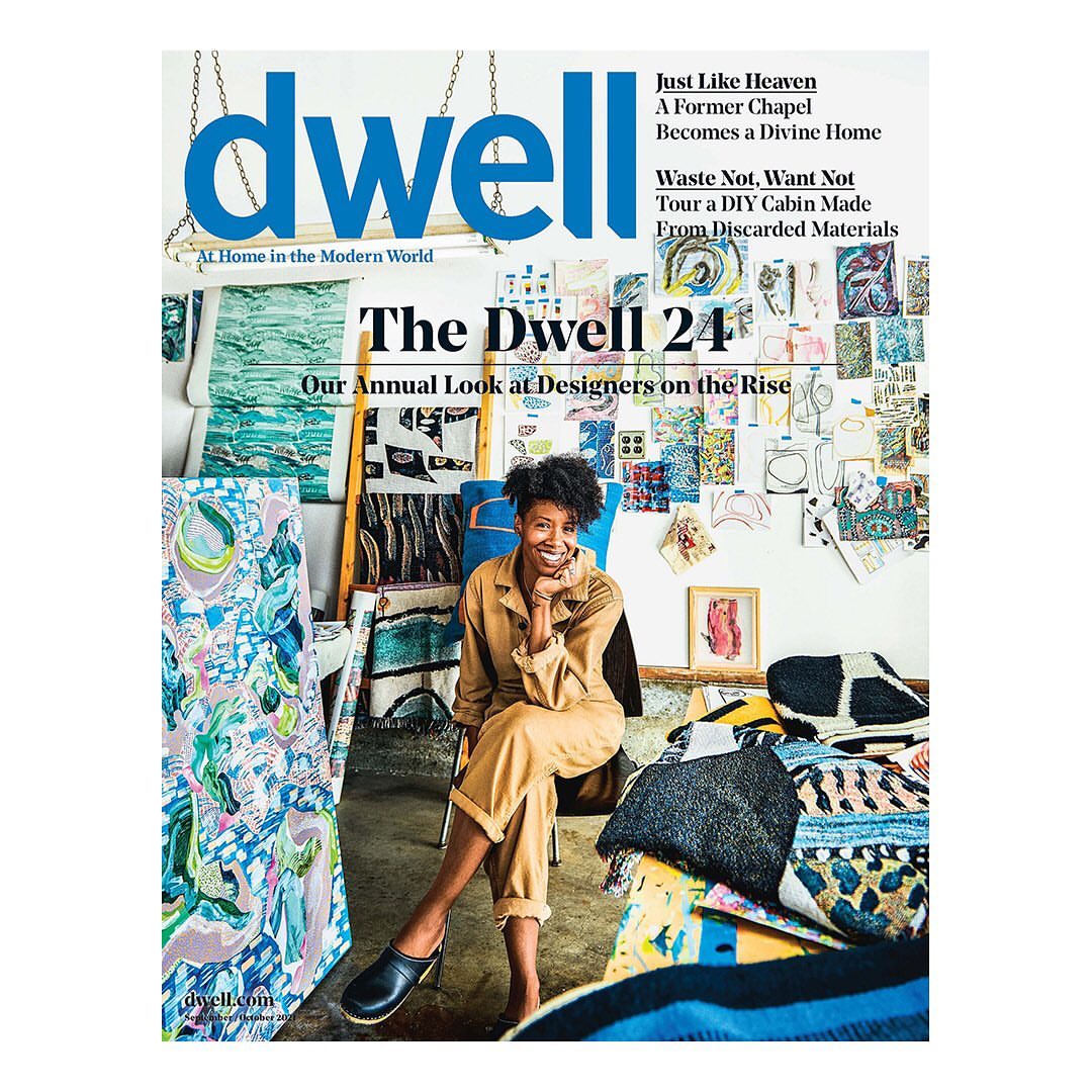 Magazine cover featuring a smiling woman in a tan jumpsuit, seated in a room filled with art and design objects, promoting 'Dwell'.