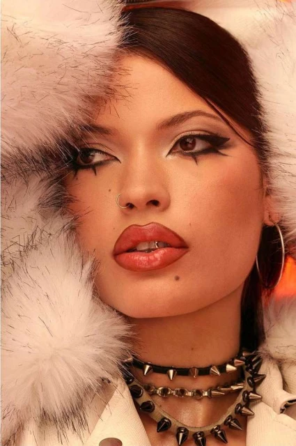 Close-up portrait of a young adult woman with dramatic makeup and a fur-trimmed hood, highlighting beauty and fashion elements.