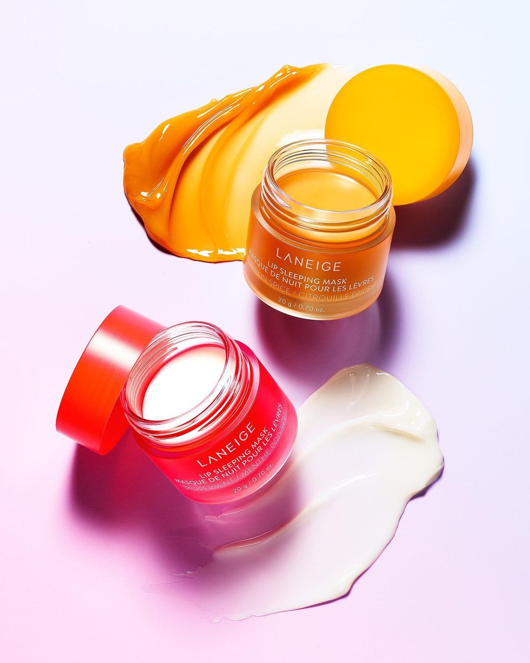 Two jars of Laneige Lip Sleeping Mask, one pink and one orange, with matching smears on a lavender and white background.