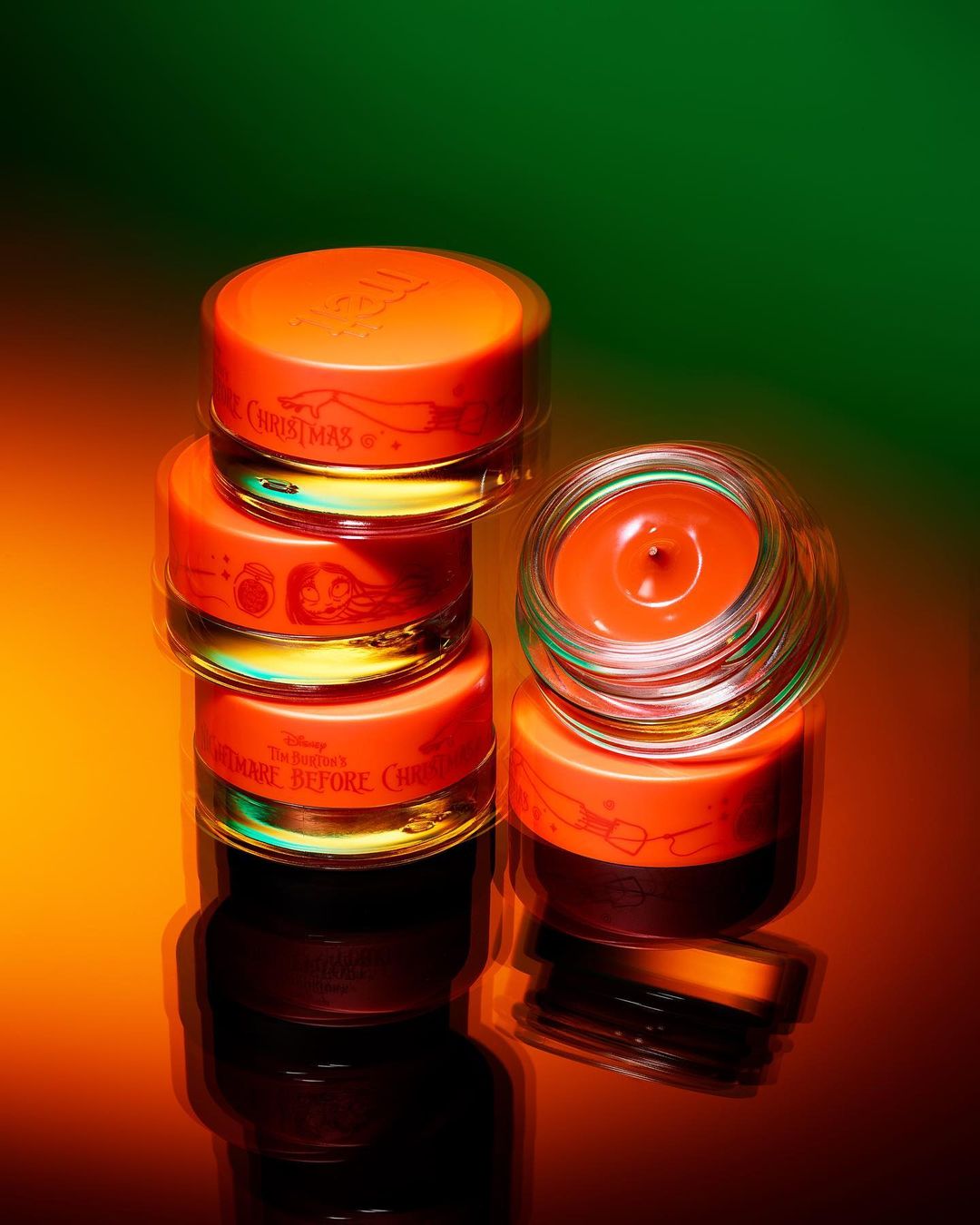 Stacked skincare products with orange lids and clear jars, featuring designs from Disney's The Nightmare Before Christmas.