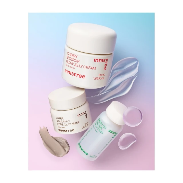 Innisfree skincare product containers: Cherry Blossom Glow Jelly Cream, Super Volcanic Pore Clay Mask, and Green Tea Enzyme PHA Toner on gradient backdrop.