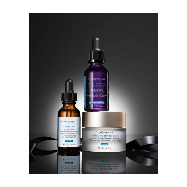 Three SkinCeuticals products including serum and cream on a reflective surface against a gradient dark gray background with ribbon.