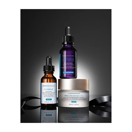 Three SkinCeuticals products including serum and cream on a reflective surface against a gradient dark gray background with ribbon.