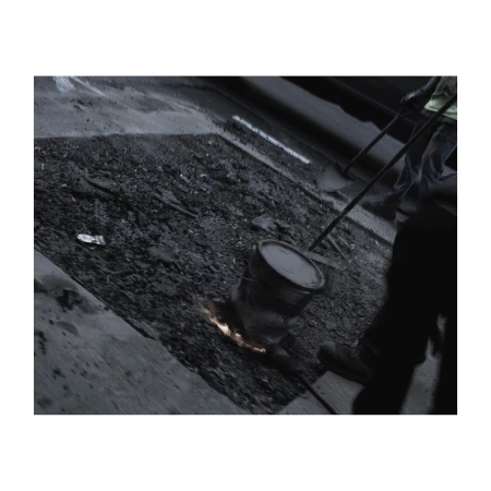 Construction worker performing road repair with molten material and a bucket in an urban environment, grayscale color palette.