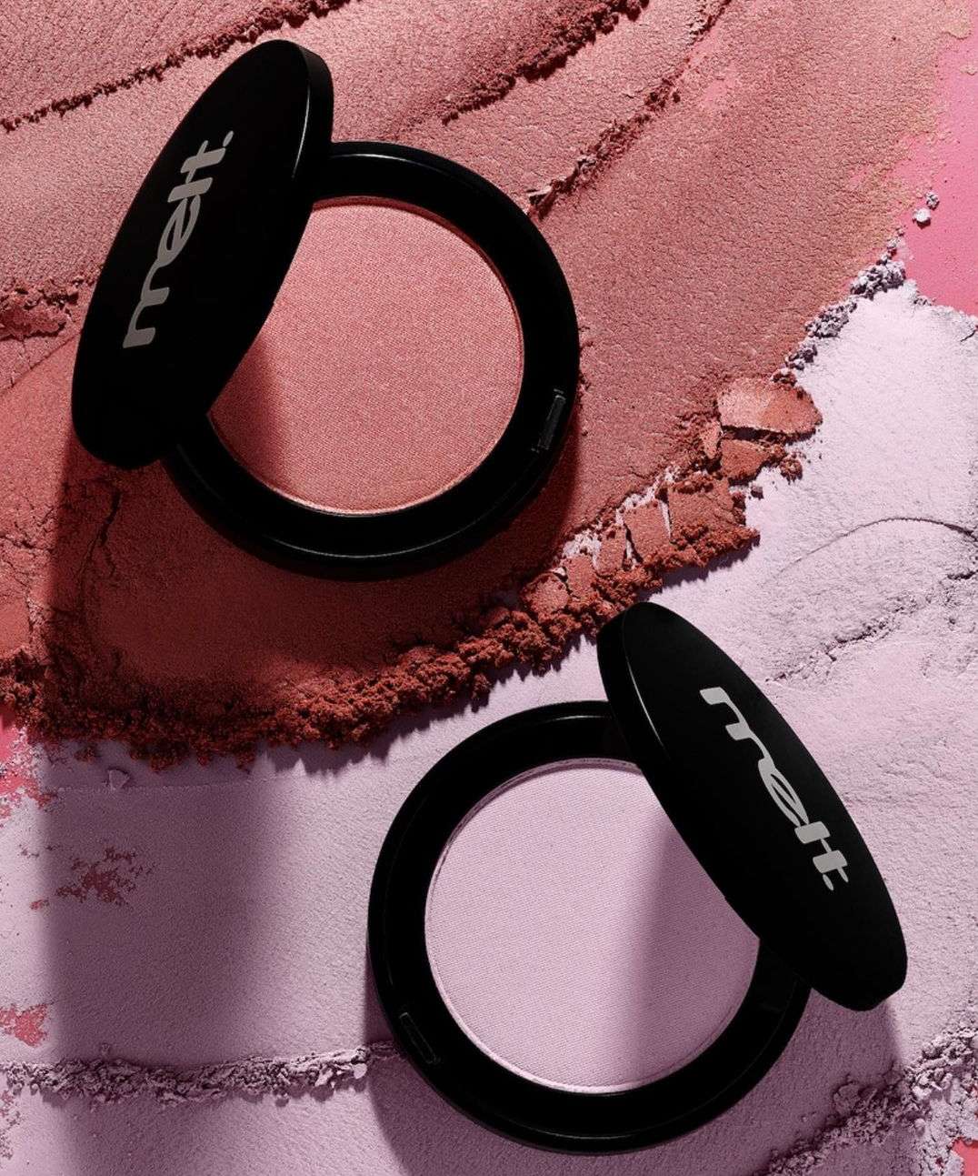 Two blush compacts sit on top of loose blush powder in shades of pink and mauve; makeup flat lay, beauty product, cosmetic